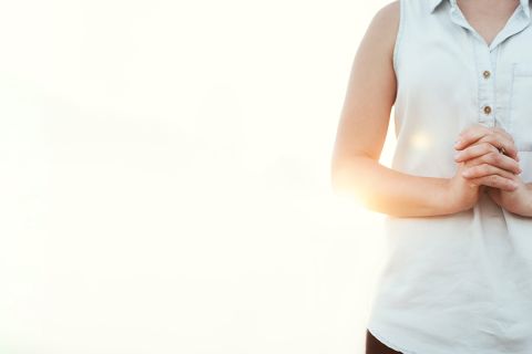 Photo of the torso of a woman standing with hands clasped to illustrate the article about 