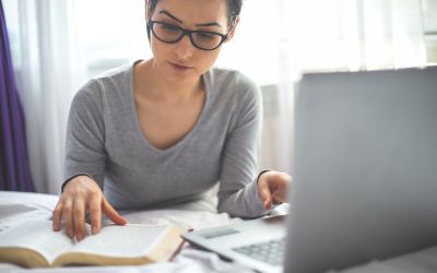 Photo of a woman reading a Bible in front of a computer to illustrate the article The Best Bible Study Tools Online