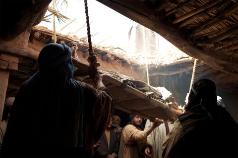 Photo illustration of a man being lowered through a roof to illustrate one of Jesus' healings, for the article What Can We Learn From Jesus’ Early Healings?